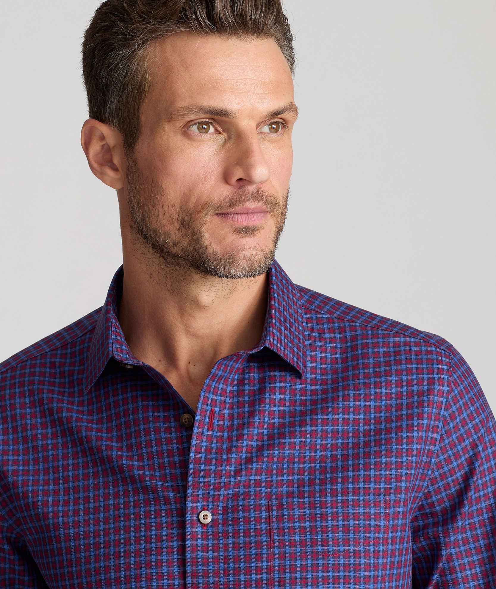 Model is wearing UNTUCKit Knight wrinkle-free long sleeve in maroon and purple navy check.