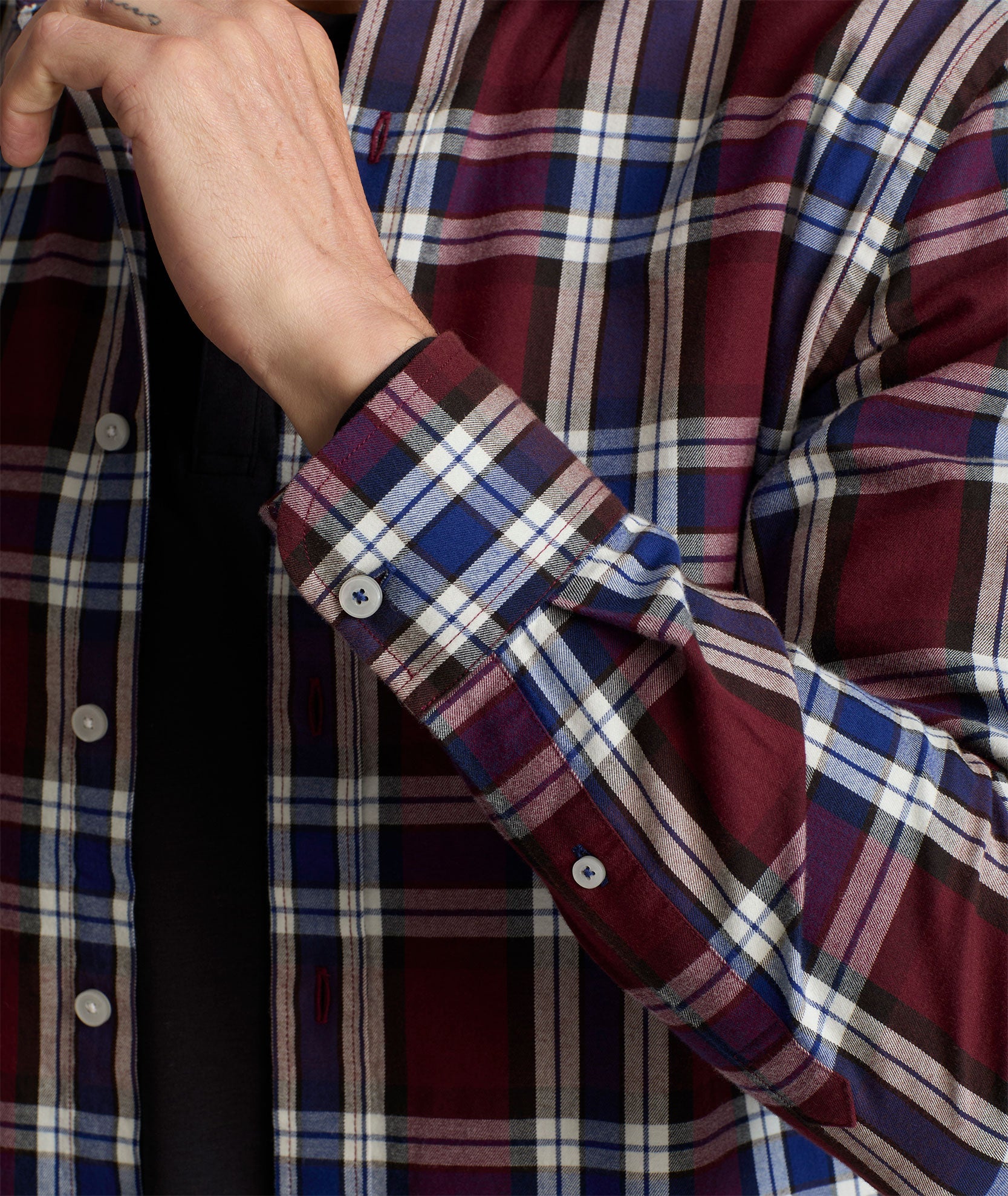 Model is wearing UNTUCKit Larson flannel in maroon grounded blue plaid. 