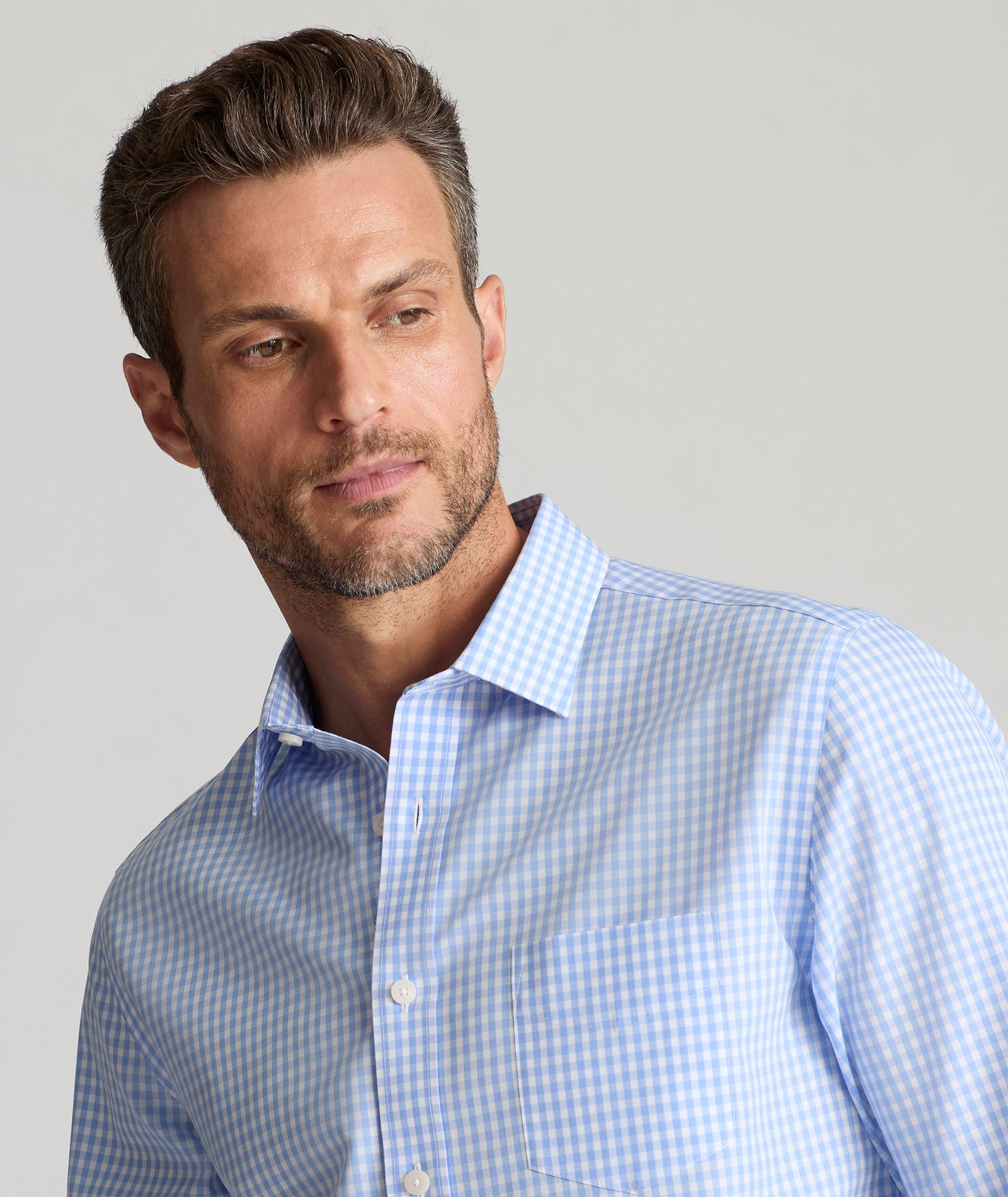 Model is wearing UNTUCKit Lawrence wrinkle free in light blue gingham. 